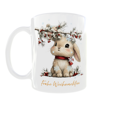 weiße Tasse mit Häschen mit rotem Schal, das unter einem beschneiten Zweig sitzt, untendrunter steht Frohe Weihnachten