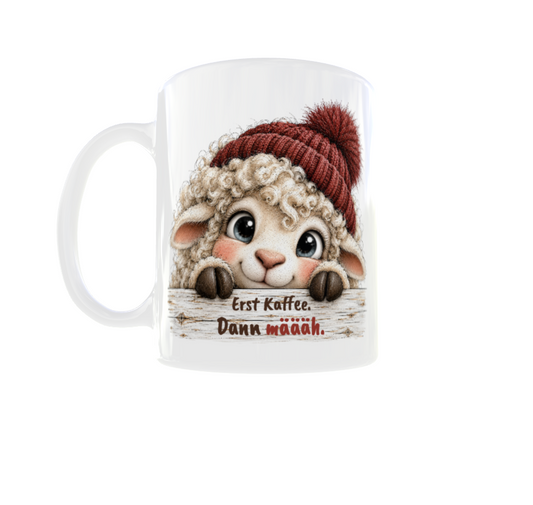 Weiße Tasse mit niedlichem Schäfchen, roter Bommelmütze und Spruch „Erst Kaffee. Dann määäh.“
